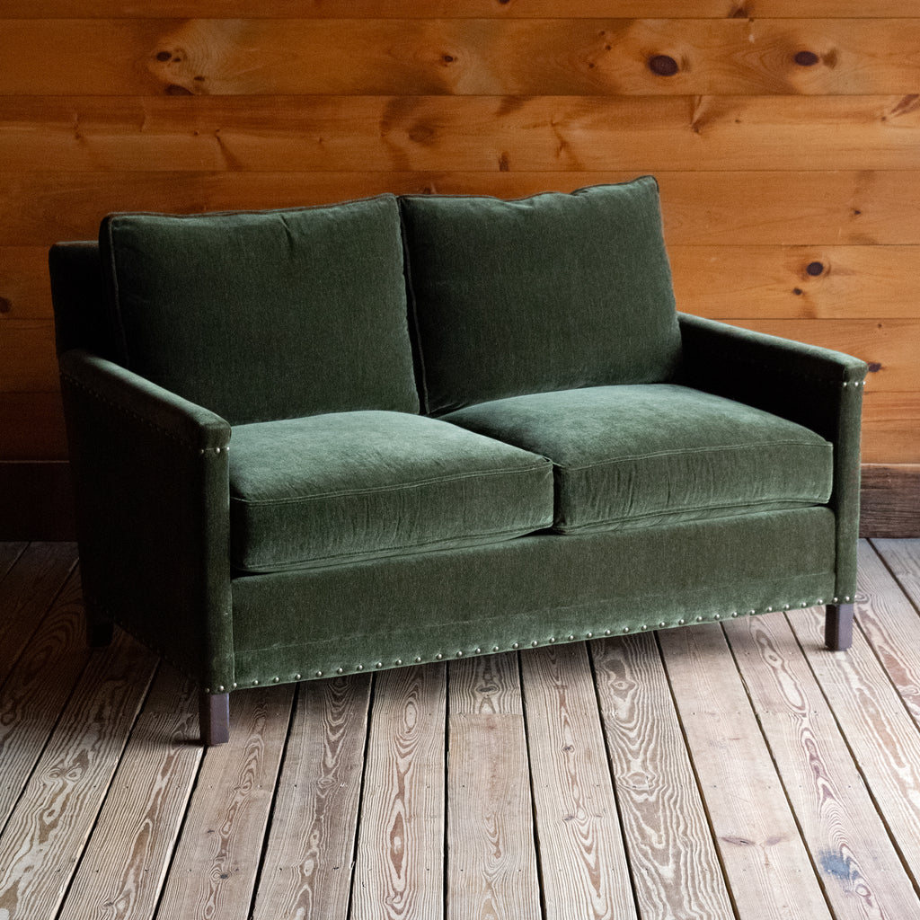 Loose back loveseat upholstered in a green velvet fabric with track arms and nailhead trim, Angled front view