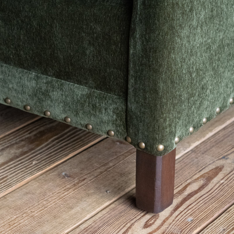 Loose back loveseat upholstered in a green velvet fabric with track arms and nailhead trim, Leg detail