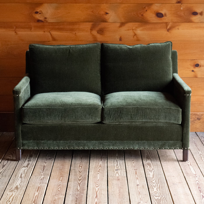 Loose back loveseat upholstered in a green velvet fabric with track arms and nailhead trim, Front view